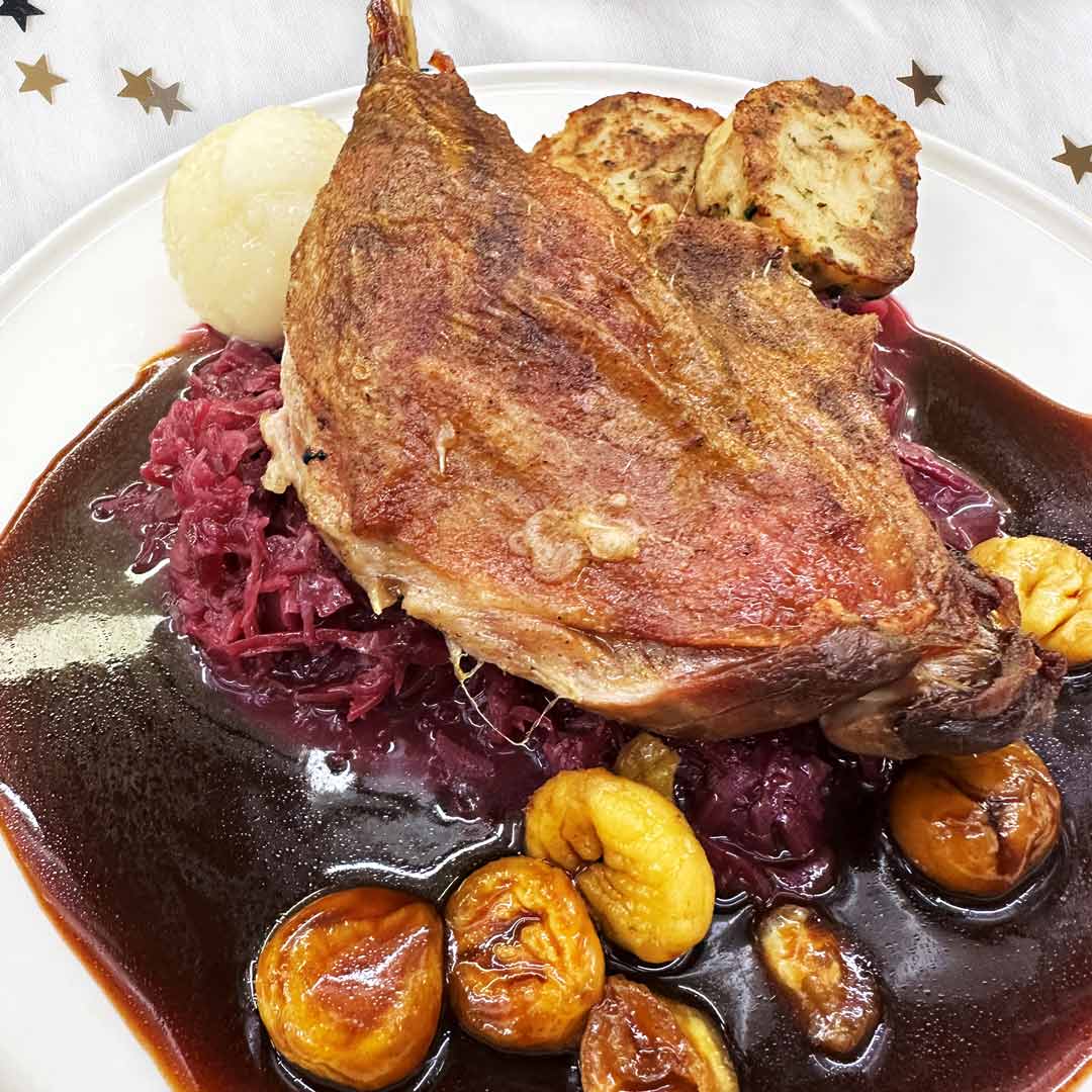 Knusprige Gänsekeule mit Rotweinsoße, Apfel-Rotkraut, glasierte Maronen, Kartoffel- & Serviettenknödel